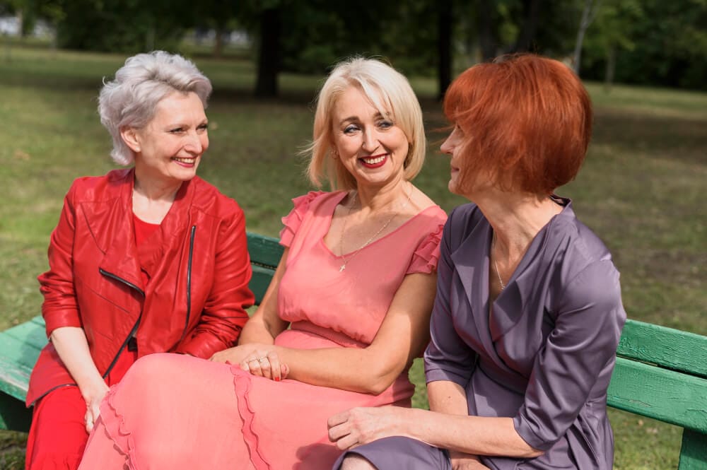 3 older women having a happy conversation anout medical marijuana for seniors on a park bench